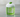 A minimalist glass with green liquid, large clear ice block, white foam, and a basil garnish.