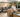 A candid-style shot of a woman plating food at an outdoor kitchen counter while friends chat in the background around a fire pit seating area.