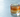 a large clear block of ice sitting nearly invisible inside the glass, barely distinguishable from the liquid around it, a single freeze-dried lime wheel resting flat on the surface undisturbed