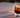 A single, crystal-clear 2.5-inch ice sphere resting in a heavy-bottomed crystal glass. The glass contains a deep, mahogany-toned liquid (Cold Brew) with visible density layers—darker at the base, slightly lighter near the surface where it meets the ice.