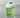 A minimalist glass with green liquid, large clear ice block, white foam, and a basil garnish.